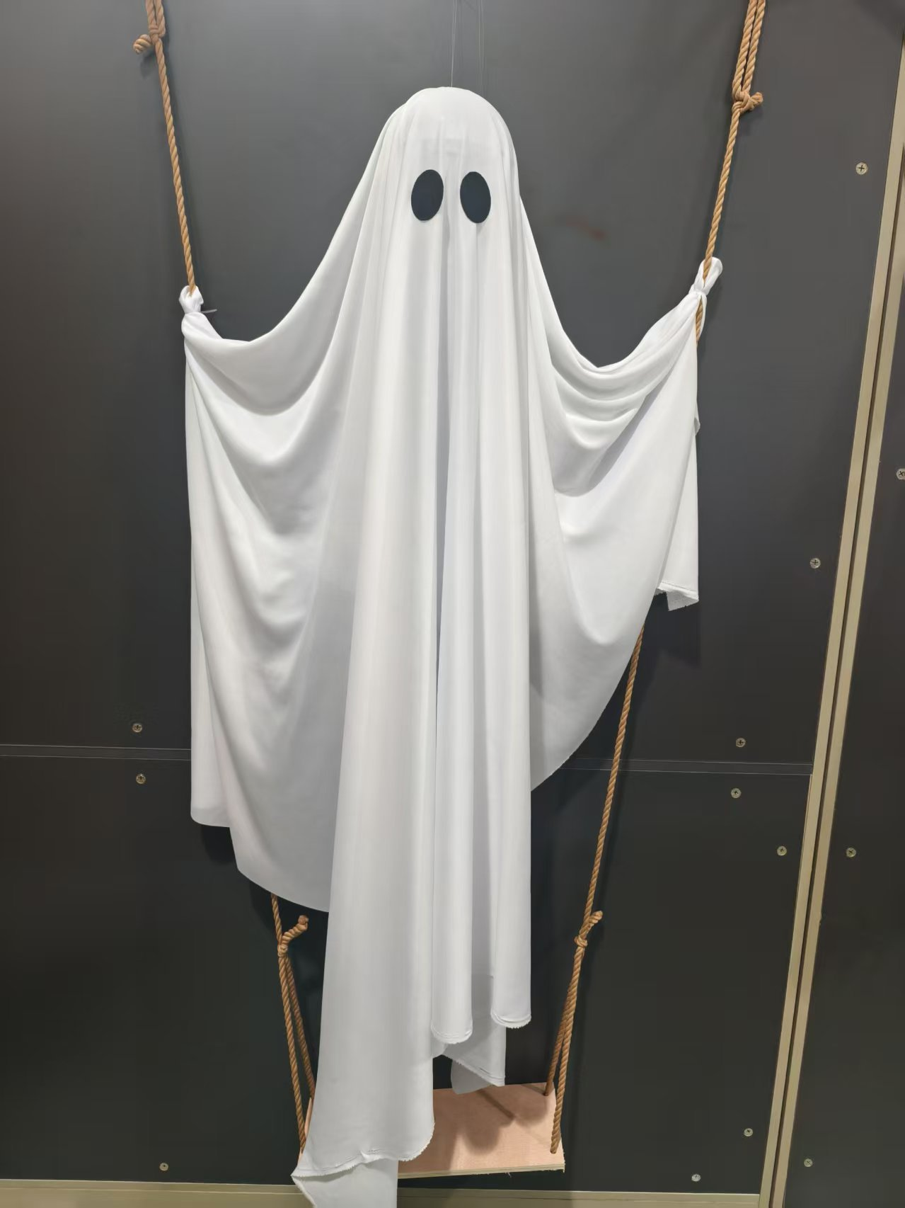 Close-up view of a white ghost seated on a rope swing